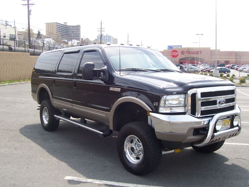 Black lifted Ford Excursion SUV with chrome brush guard and off-road tires in parking lot