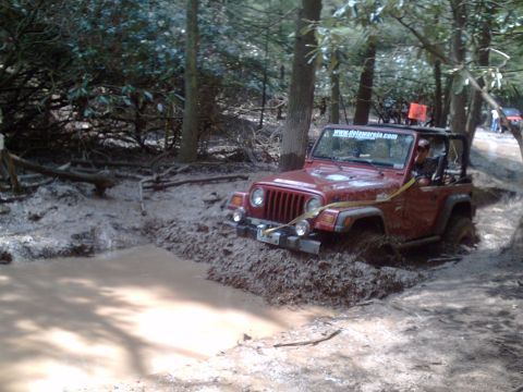 1991 Ford Bronco - This Jeep is deep in the mud, with a second vehicle visible further down the trail.