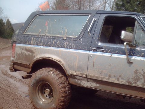 1991 Ford Bronco - Muddy Ford Bronco navigates off-road terrain.