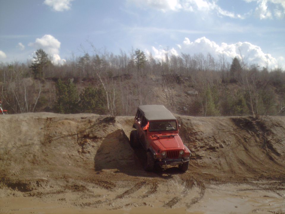 Red Jeep Wrangler climbing a dirt hill