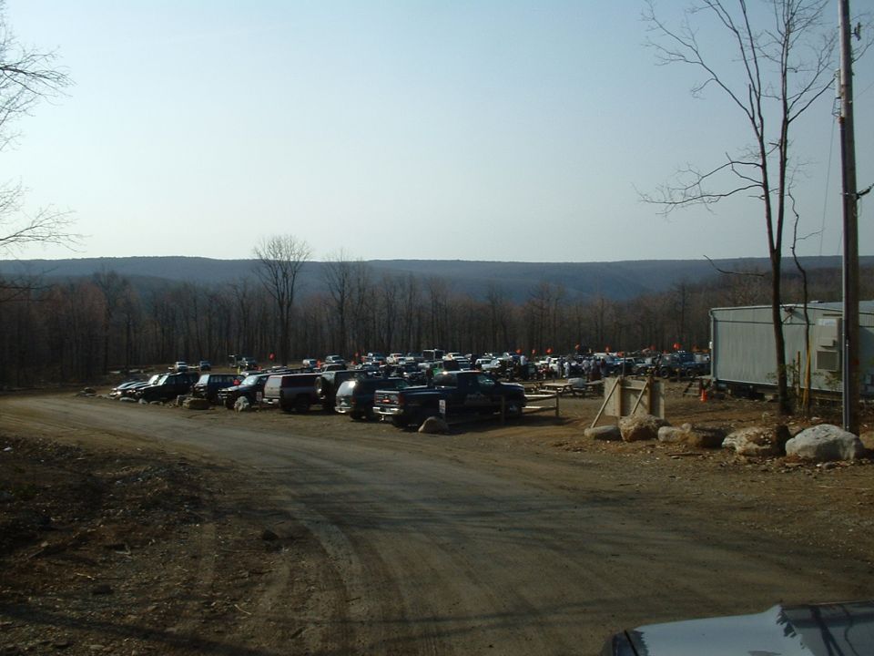 Parking lot filled with SUVs and trucks in a wooded area