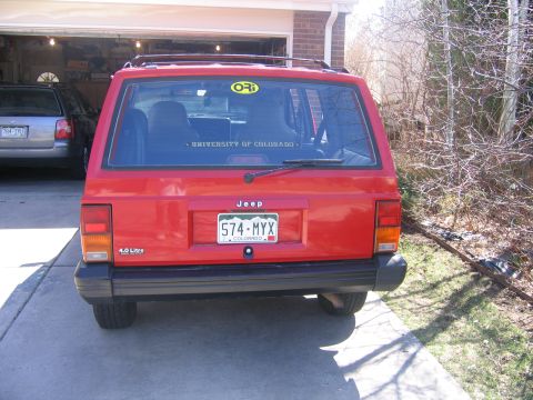 1996 Jeep Cherokee - Rear view of a red 1996 Jeep Cherokee parked in a driveway, with another vehicle visible in the garage.