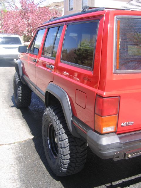 1996 Jeep Cherokee - A red Jeep Cherokee is parked outside a house with a flowering tree in the background.