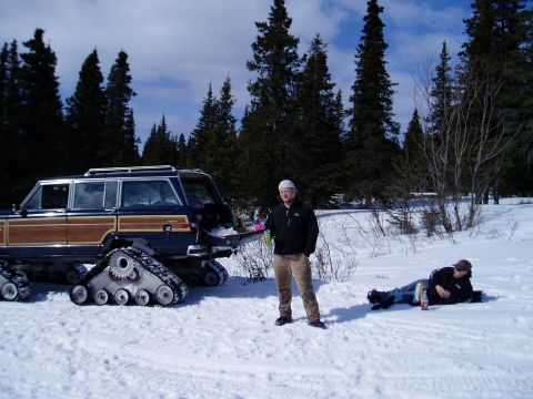2000 Ford E350 - A modified wood-paneled SUV equipped with tracks sits in a snowy landscape with two people nearby.