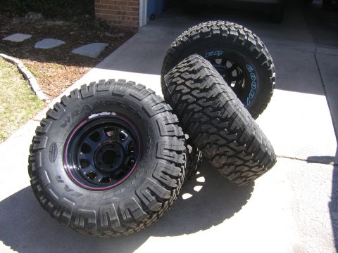1996 Jeep Cherokee - Three off-road tires are shown, two mounted on black rims with a purple accent stripe.