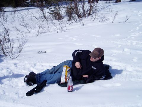 2000 Ford E350 - A person rests in a snowy landscape, with a drink and snacks nearby.