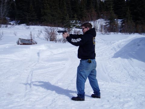 2000 Ford E350 - A man fires a handgun in a snowy, wooded area.