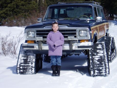 2000 Ford E350 - A Jeep Grand Wagoneer equipped with snow tracks stands in a snowy landscape.