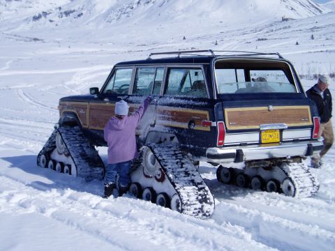 2000 Ford E350 - A Jeep Grand Wagoneer equipped with snow tracks navigates a winter environment.