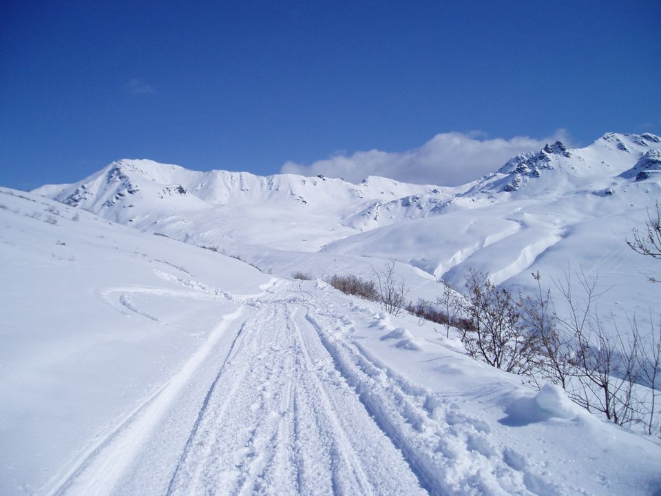Snowy mountain pass with tire tracks and a blue sky