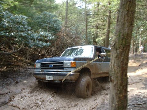 1991 Ford Bronco - A blue 1991 Ford Bronco tackles a challenging muddy off-road course.