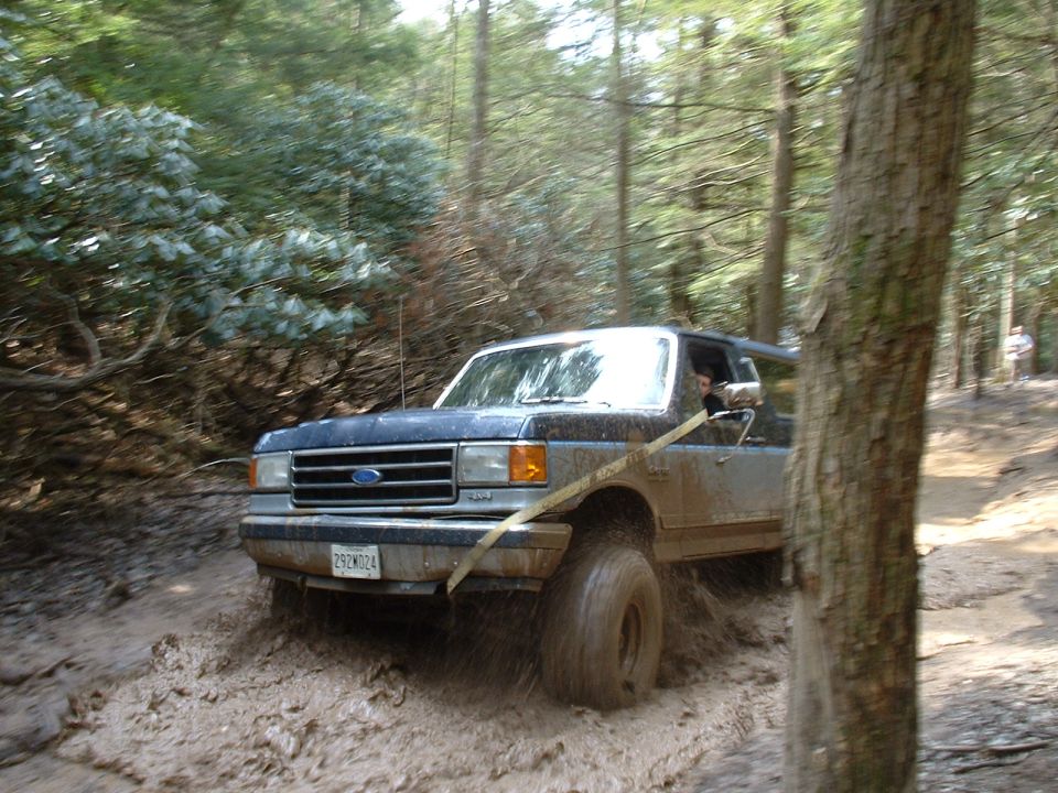 Blue 1991 Ford Bronco navigating a muddy trail