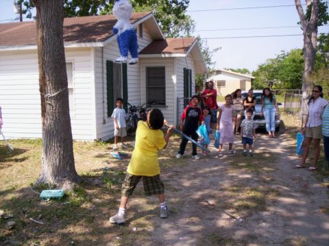 1986 Ford Bronco - A group of people, including children, are gathered for an outdoor piñata party, with one child swinging a bat.
