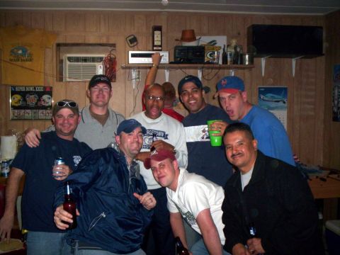 1986 Ford Bronco - A group of men gather for a photo in a room decorated with sports memorabilia and a shelf of electronics.