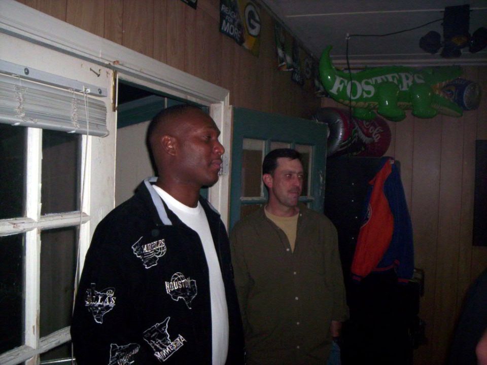 Two men stand in a room with decorations on the wall