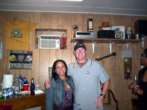 1986 Ford Bronco - A man and woman pose for a photo in a room decorated with sports memorabilia and personal items.
