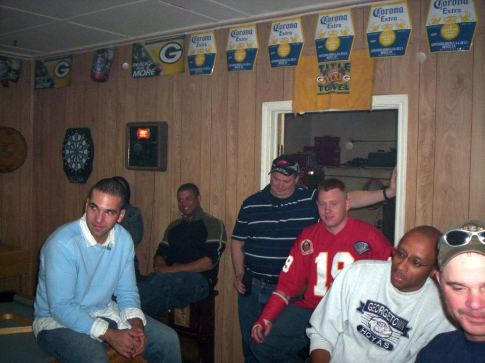 Men gathered in a room decorated with Corona beer banners and Green Bay Packers flags