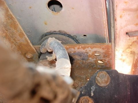 1987 Ford Bronco - Close-up view of a corroded vehicle frame showing a wire conduit and fasteners.