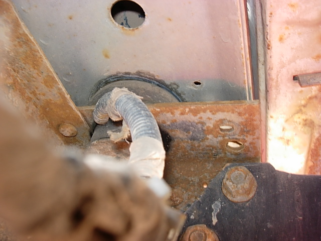 rusted frame section with a corrugated wire loom and mounting bolts