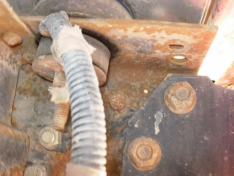 1987 Ford Bronco - Close-up of a corroded metal bracket and wiring, indicating significant rust and damage.