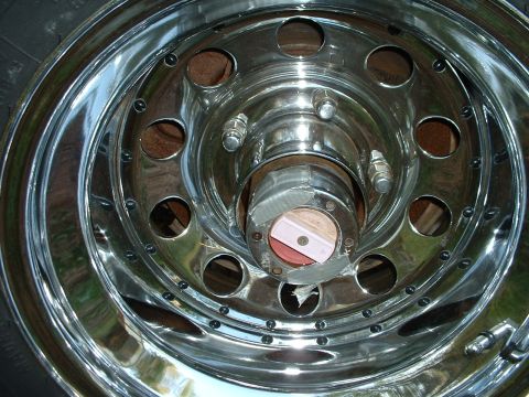 1985 Ford Bronco - Close-up of a chrome wheel and hubcap, showing details of the lug nuts and a taped hub.