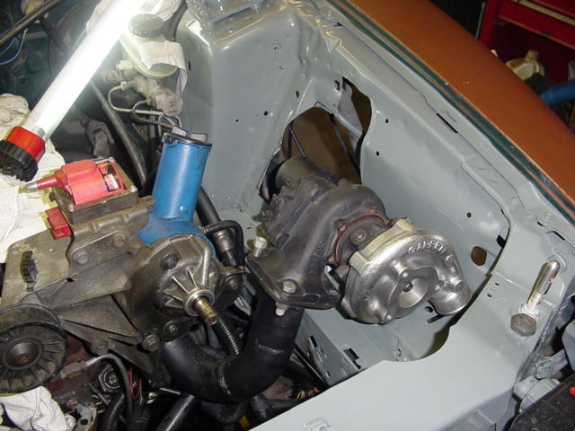 engine bay with a turbocharger installed, showing exhaust manifold and intake piping