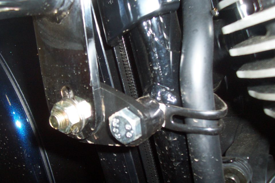 Close-up of motorcycle engine with visible bolt and hose clamp