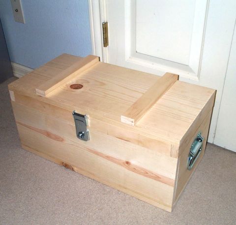 1996 Ford Bronco - A wooden chest with metal hardware sits on a carpeted floor in front of a door.