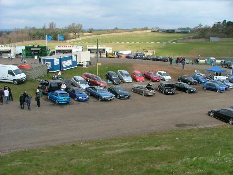 2001 Ford Fiesta - A scene of an outdoor event with multiple vehicles parked near food stalls and a grassy field.