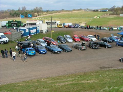 2001 Ford Fiesta - An outdoor gathering features a variety of vehicles parked near food vendors and a large grassy area.
