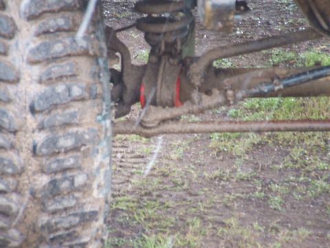 1989 Ford Bronco - Mud-covered front axle and suspension parts are visible in this close-up view.