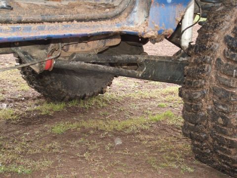 1989 Ford Bronco - Close-up of a vehicle's suspension and tire, covered in mud.