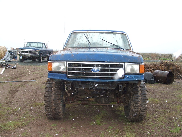 Blue Ford pickup truck with lifted suspension and large tires, front view