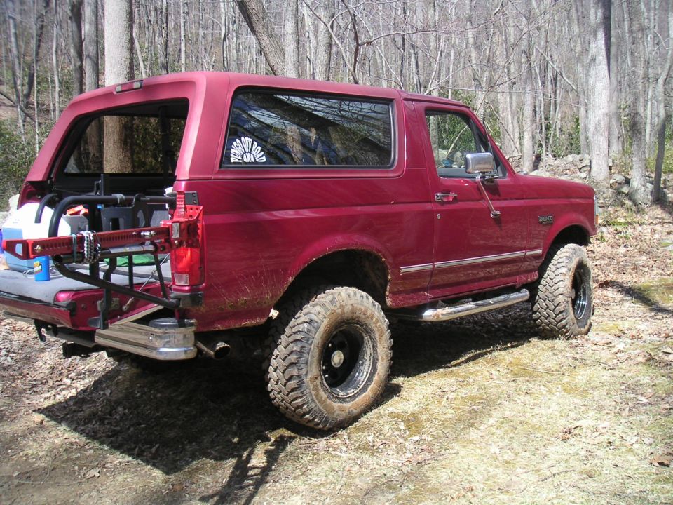 Red 1994 Ford Bronco with off-road tires and high-lift jack