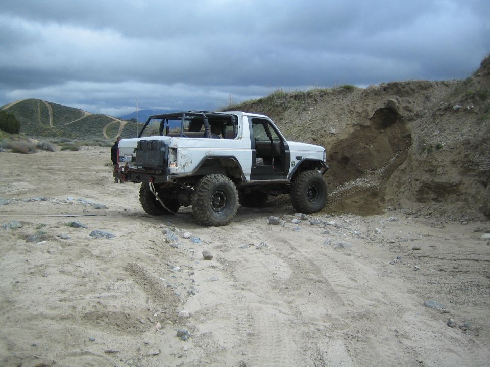 White off-road SUV with roll cage on sandy terrain