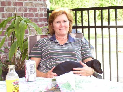 1992 Ford Bronco - A woman relaxes on a patio with her dachshund, a can of soda, and a bottle of sauce on the table.