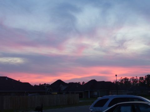 1992 Ford Bronco - A silver SUV is parked on a street during a colorful sunset.