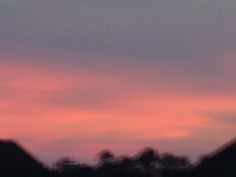 1992 Ford Bronco - A colorful sunset paints the sky above a dark, silhouetted landscape of trees and rooftops.