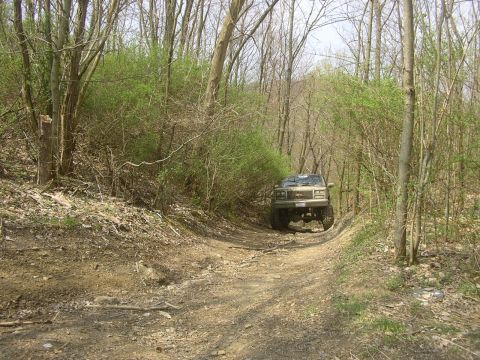 1989 GMC Jimmy - A 1989 GMC Jimmy navigates a wooded trail, kicking up dust on the dirt path.