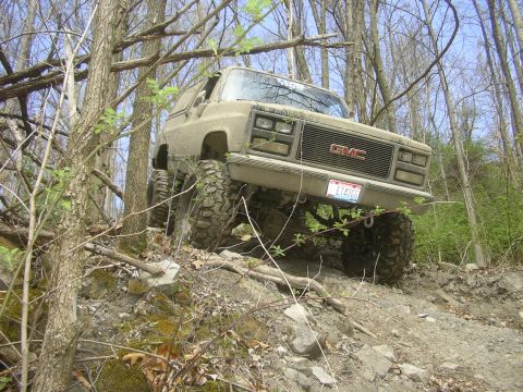 1989 GMC Jimmy - Modified 1989 GMC Jimmy tackling a challenging off-road course in a wooded area.