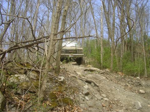 1989 GMC Jimmy - A 1989 GMC pickup truck navigates a challenging off-road path through a forest.