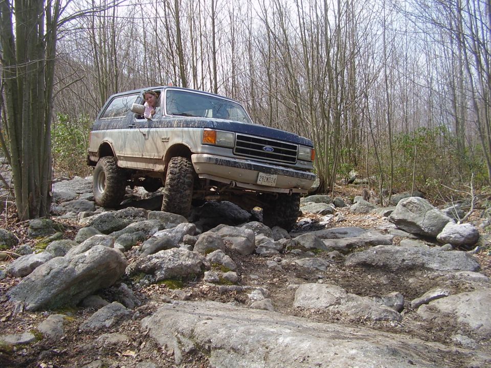1987 Ford Bronco navigating a rocky forest trail
