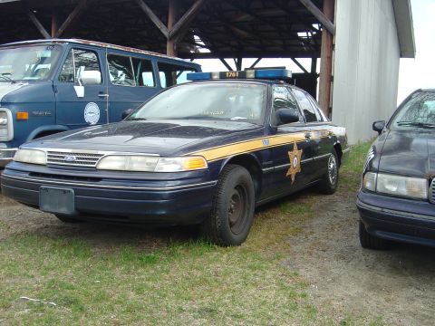 2001 Ford Crown Victoria - This police car, likely a 1998 model, is parked outdoors under a covered structure.