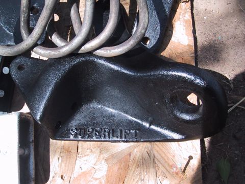 1990 Ford Bronco - Close-up of black metal suspension parts, including a bracket with "SUPERLIFT" text and coil springs.