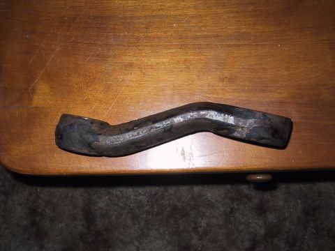 1990 Ford Bronco - A single, curved metal part is shown resting on a wooden surface.
