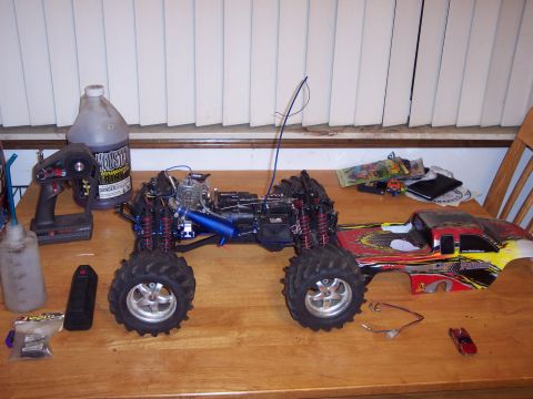 1974 Ford Bronco - A disassembled remote-controlled monster truck sits on a table next to its controller and fuel.