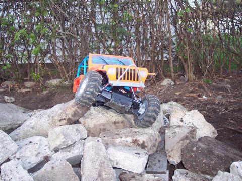 1974 Ford Bronco - An orange remote control rock crawler navigates a rocky terrain.