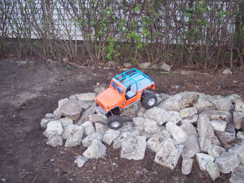 1974 Ford Bronco - An orange remote control vehicle navigates a rocky terrain.