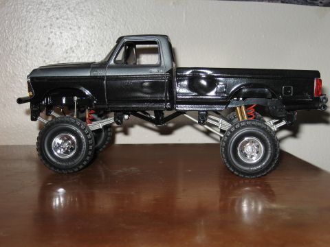 1977 Ford F-150 - A model truck with a two-tone paint job and custom suspension sits on a wooden surface.