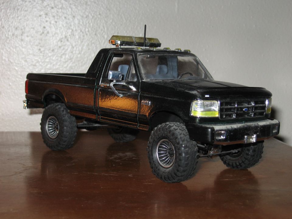 Black model truck with amber light bar on roof